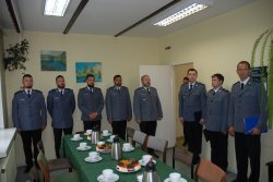 zdjęcie przedstawia ośmiu umundurowanych policjantów, stoją oni na baczność, policjanci znajdują się w sali Komisariatu Policji w Przygodzicach.