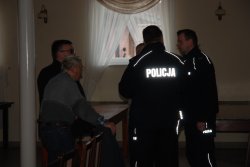 Dwóch umundurowanych policjantów rozmawia z uczestnikami debaty.